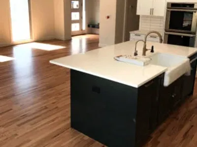 new hardwood floors in updated kitchen with black cupboards and white countertops