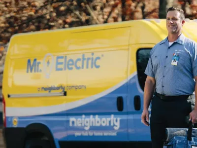 Male electrician standing in front of Mr. Electric branded van.