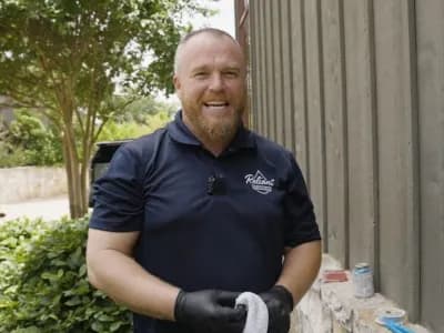 max hicks, owner of reliant plumbing, standing outside of a building holding a rag and smiling