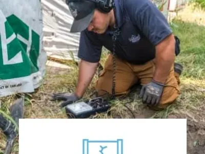 man on grass outside using a device to diagnose plumbing problem