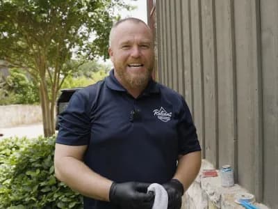 max hicks, owner of reliant plumbing, standing outside of a building holding a rag and smiling