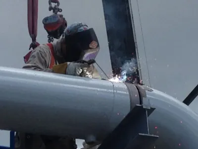 Close Up Of Person Wearing Safety Mask Welding On Metal Pipe