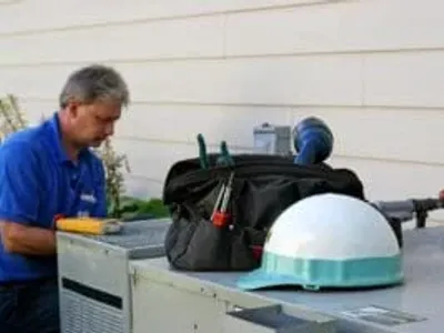 HVAC technician servicing outdoor air conditioning unit during emergency repair