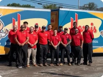 A group of Harris employees pose in front of two company trucks.