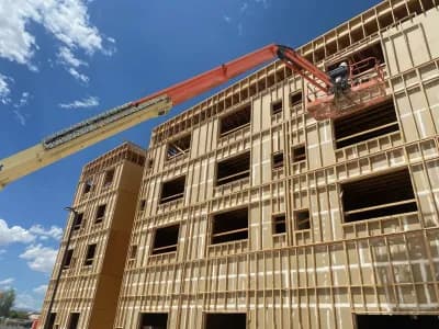Wood-framed building under construction with a crane overhead.