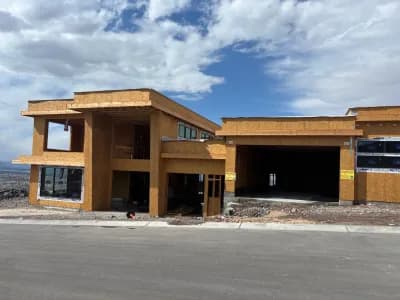 A large, unfinished house under construction with wooden framing.