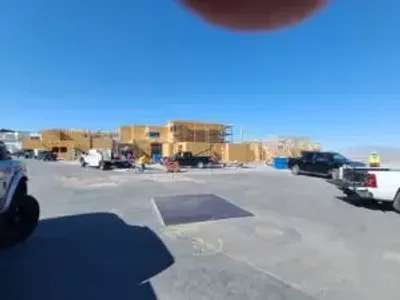 Construction site with wooden framing under clear blue sky.