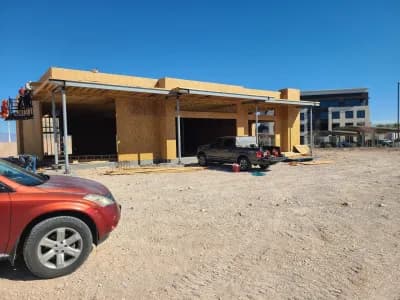 Construction site with vehicles and wooden framework under a clear sky.