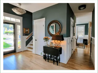 Cozy entryway with a staircase, mirror, and a piano bench.