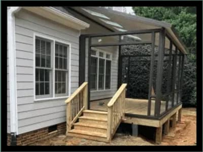 A wooden porch with stairs and a black screened enclosure.