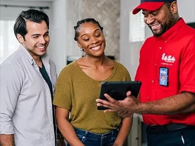 Mr. Rooter Plumbing professional showing two customers something on a tablet.