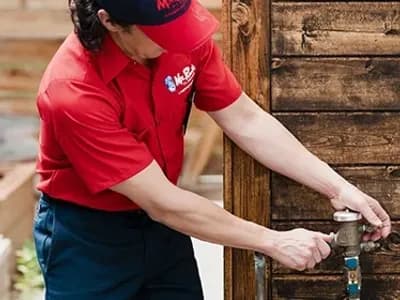 Mr. Rooter Plumbing professional turning on a water spigot.