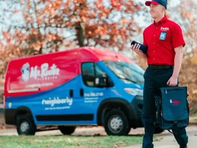 Mr. Rooter professional walking up to a home with a branded van in the background.