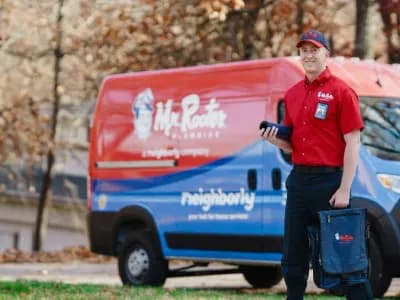 Mr. Rooter service professional standing beside a branded van.