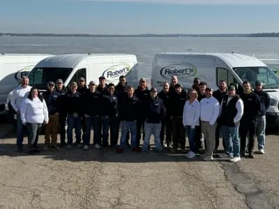 Robert's Plumbing team standing in front of work vans parked next to a lake in Madison, Wi. Team is posing together