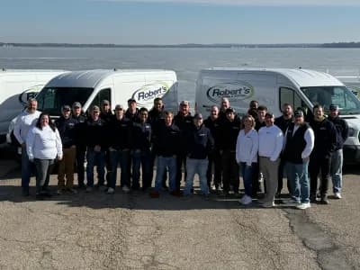 Robert's Plumbing team standing in front of work vans parked next to a lake in Madison, Wi. Team is posing together