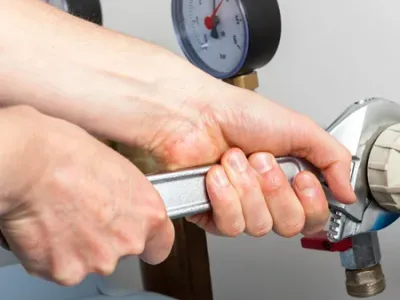 Hands repairing valves in boiler room