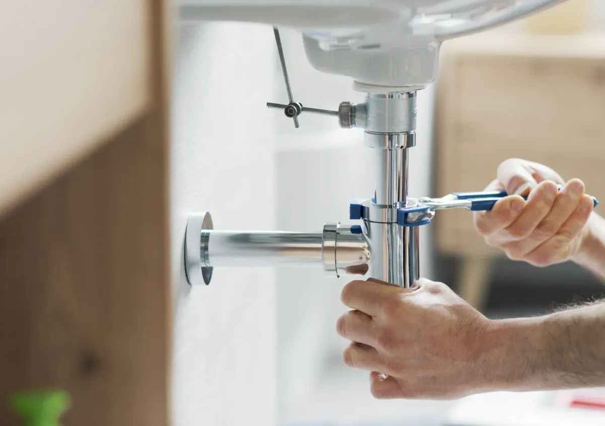 Plumber hands using a wrench to tighten a pipe