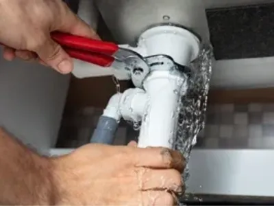 Close-up Of Male Plumber Fixing White Sink Pipe With Adjustable Wrench