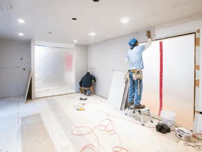 Workers installing drywall in a room.