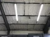 The industrial ceiling features two fluorescent lights and insulation expertly installed by a top-tier insulation contractor. Metal beams support the structure, and
