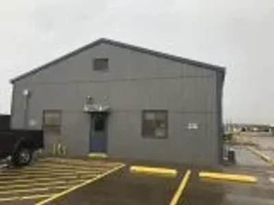 A grey corrugated metal building with a sign reading