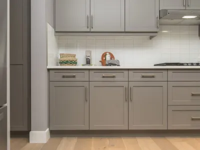 Modern kitchen featuring custom gray cabinetry, solid surface countertops, and stylish under-cabinet lighting, emphasizing functionality and aesthetics.