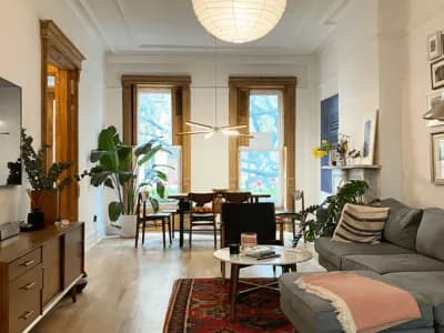 Modern living room with stylish furniture, under-cabinet lighting, large windows, and plants, showcasing a blend of comfort and elegance for enhanced interior ambiance.