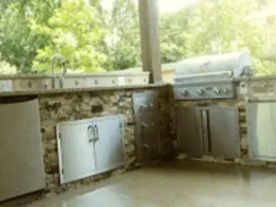 Outdoor kitchen featuring custom stone cabinetry, stainless steel appliances, and a grill, designed for functionality and style in home remodeling.