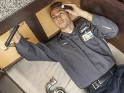HARP Home Services technician operating plumbing repairs on a kitchen sink