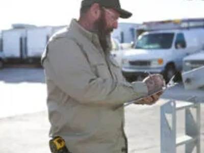 Commercial electrician inspecting an electrical installation project and taking notes on a clipboard