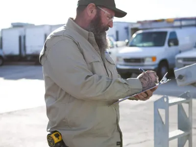 Commercial electrician inspecting an electrical installation project and taking notes on a clipboard