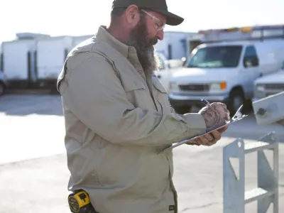 Commercial electrician inspecting an electrical installation project and taking notes on a clipboard