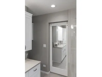 White cabinets with tan granite countertops and a white door with a mirror on the wall
