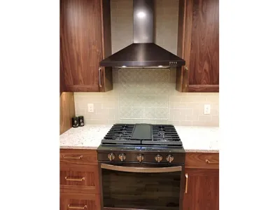 Remodeled kitchen with new wood cabinets and a brand new stove with a fan above it