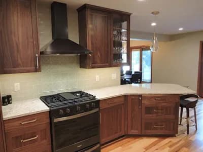 Newly renovated kitchen with wood cabinets and a black stove with hard wood floors