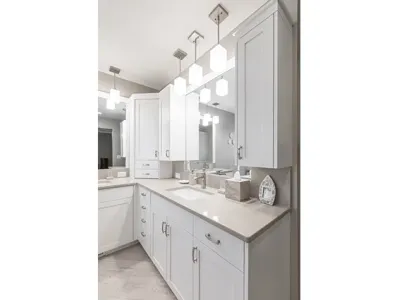 Remodeled white bathroom cabinets with tan granite countertops and a wood floor