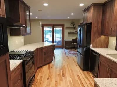 Remodeled kitchen with new dark wood cabinets and appliances with a curved bar side eating area