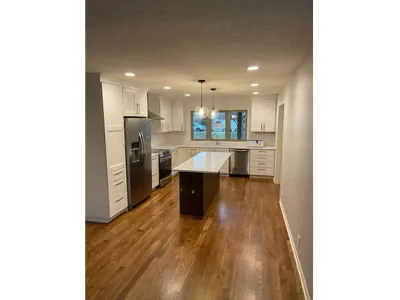 Fully remodeled kitchen with hardwood floors and a black island with room for stools