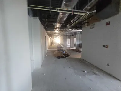 Commercial tenant buildout with drywall hung and painted walls along open ceiling corridor