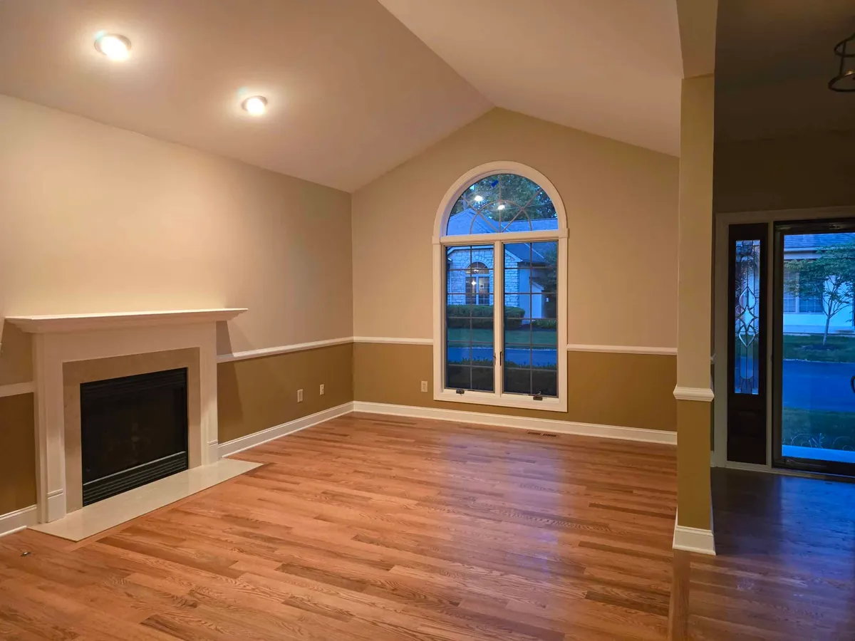 Completed residential interior painting with two-tone walls, white trim, chair rail, and vaulted ceiling