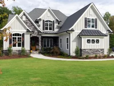 Craftsman-style home exterior with board and batten siding, stone accents, dark roof, and manicured lawn.