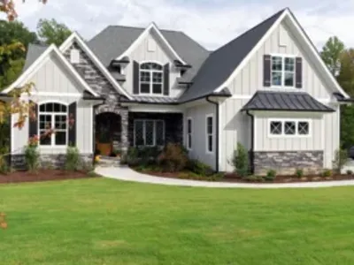 Craftsman-style home exterior with board and batten siding, stone accents, dark roof, and manicured lawn.