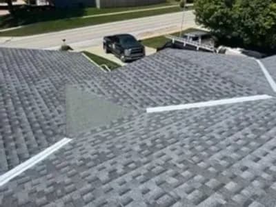 Aerial view of a residential roof mid-replacement showing new gray shingles partially installed.