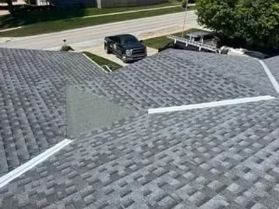 Aerial view of a residential roof mid-replacement showing new gray shingles partially installed.