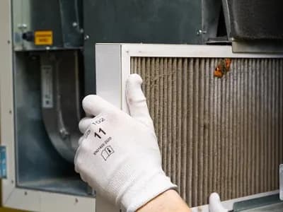 HVAC technician replacing a dirty air filter — spring AC maintenance in northern Utah