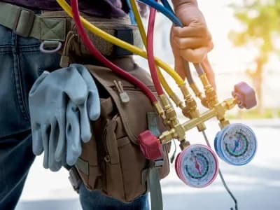 HVAC technician performing AC repair with pressure gauge