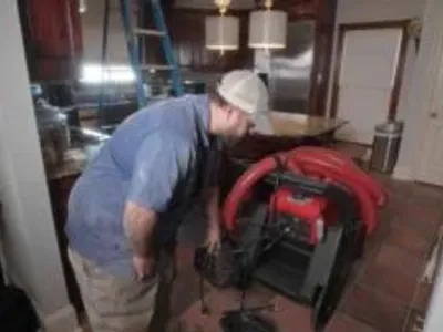 Technician preparing duct cleaning equipment in a residential kitchen to improve indoor air quality and prevent respiratory issues.