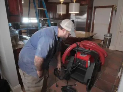 Technician preparing duct cleaning equipment in a residential kitchen to improve indoor air quality and prevent respiratory issues.