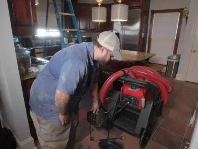 Technician preparing duct cleaning equipment in a residential kitchen to improve indoor air quality and prevent respiratory issues.